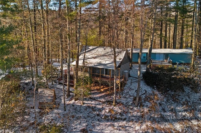 view of side of property featuring a deck, metal roof, and a view of trees