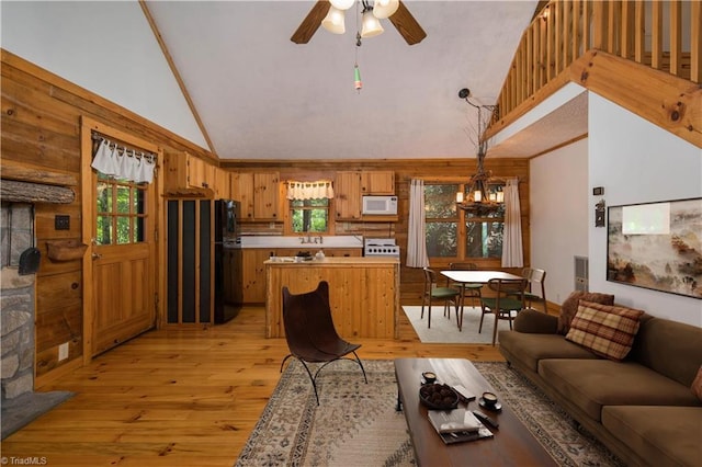 living room featuring ceiling fan with notable chandelier, light hardwood / wood-style floors, and high vaulted ceiling