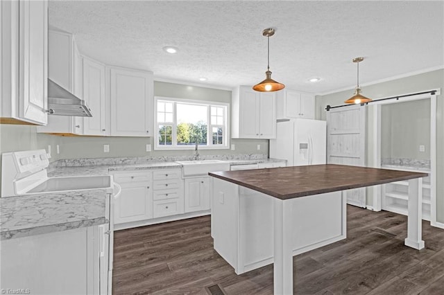 kitchen with white cabinets, white appliances, a center island, a barn door, and wood counters