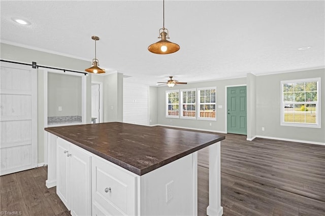 kitchen featuring a barn door, hanging light fixtures, white cabinets, and a wealth of natural light