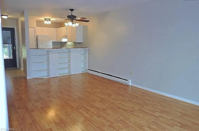 interior space with light hardwood / wood-style flooring, a baseboard radiator, white fridge, ceiling fan, and white cabinets