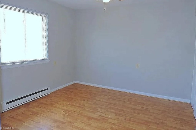 spare room featuring a baseboard heating unit and light hardwood / wood-style flooring