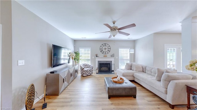 living room featuring light wood finished floors, a fireplace, and ceiling fan