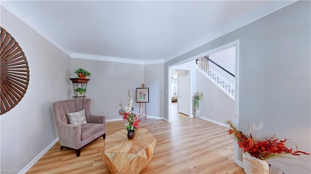 living area with stairs, crown molding, baseboards, and light wood-type flooring