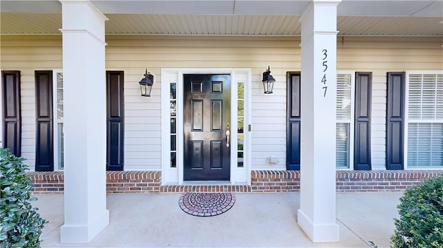 view of exterior entry with brick siding and covered porch