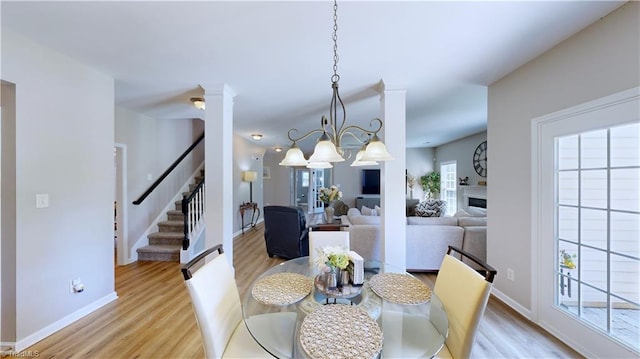 dining space with baseboards, a fireplace, wood finished floors, and stairs