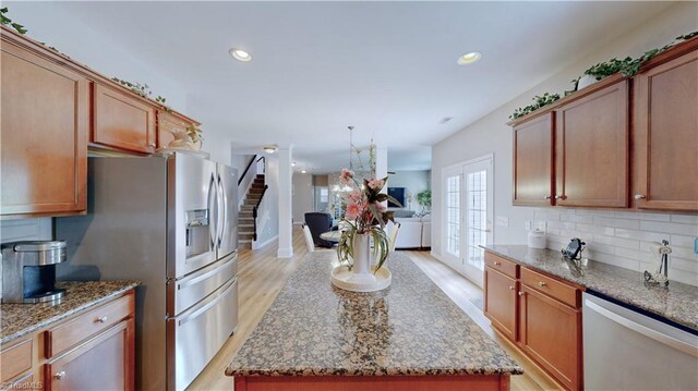 kitchen featuring appliances with stainless steel finishes, a center island, decorative backsplash, and light hardwood / wood-style flooring