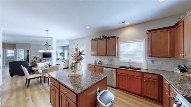 kitchen with dishwasher, light hardwood / wood-style flooring, tasteful backsplash, sink, and a center island