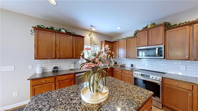 kitchen with decorative backsplash, appliances with stainless steel finishes, and dark stone counters