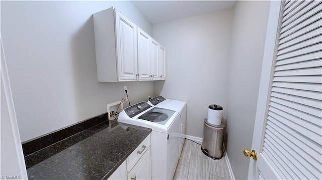 clothes washing area with cabinet space, separate washer and dryer, and baseboards