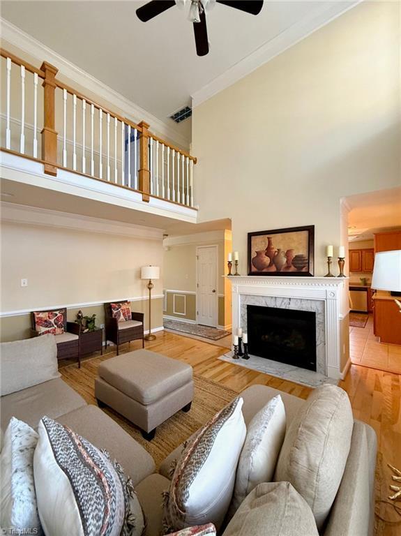 living room featuring ornamental molding, a premium fireplace, and light wood-type flooring