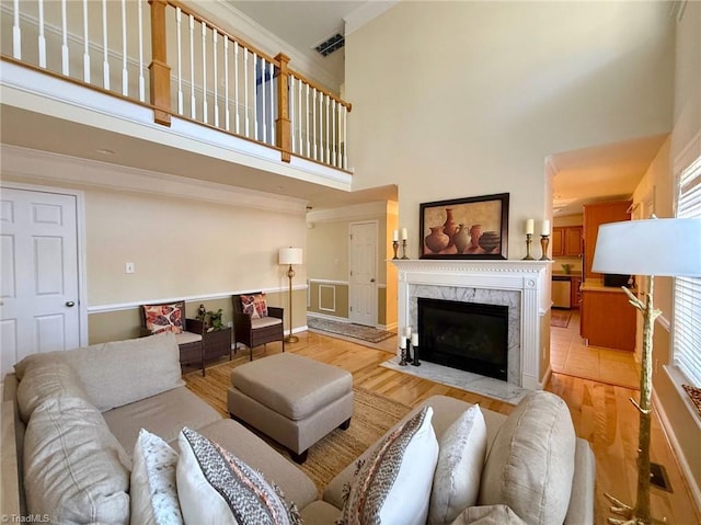 living room featuring a high ceiling, a fireplace, and light hardwood / wood-style flooring