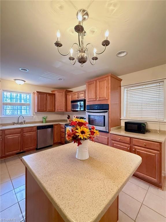 kitchen featuring stainless steel appliances, light tile patterned flooring, a notable chandelier, and a center island