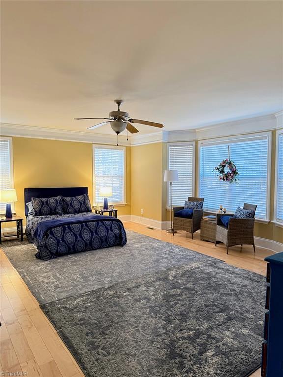 bedroom featuring hardwood / wood-style flooring, ceiling fan, and crown molding