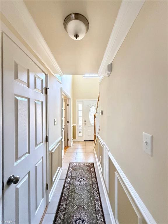 entryway with ornamental molding and light tile patterned floors