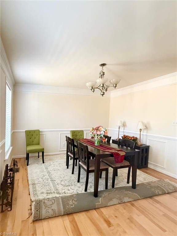 dining room with a notable chandelier, crown molding, and hardwood / wood-style flooring