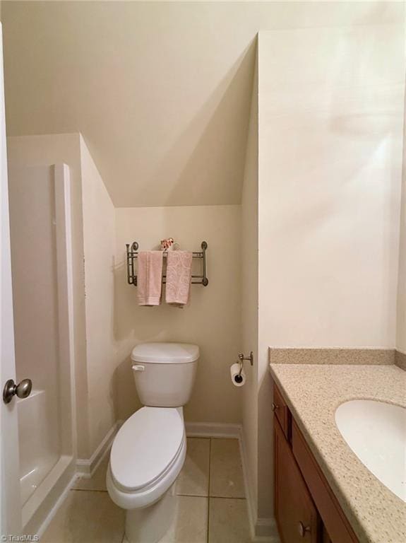 bathroom with toilet, tile patterned flooring, vaulted ceiling, and vanity