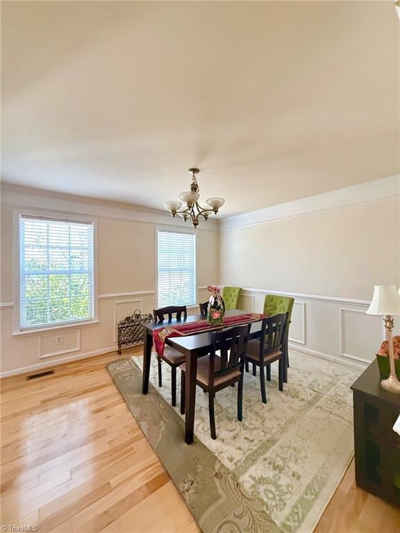 dining space with ornamental molding, an inviting chandelier, and wood-type flooring