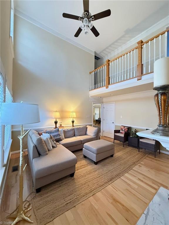 living room featuring a high ceiling, hardwood / wood-style floors, and ceiling fan