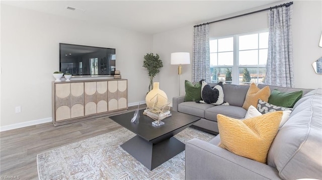 living area with baseboards, wood finished floors, and visible vents