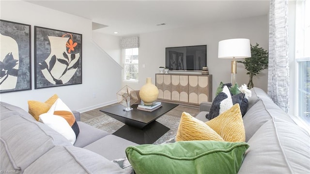 living area with baseboards, visible vents, and wood finished floors
