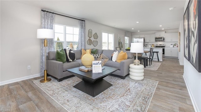 living area with recessed lighting, baseboards, and light wood-type flooring