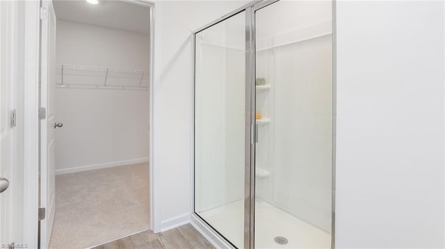 full bath featuring a walk in closet, baseboards, a stall shower, and wood finished floors