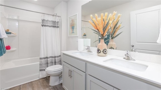 bathroom with double vanity, toilet, a sink, and wood finished floors