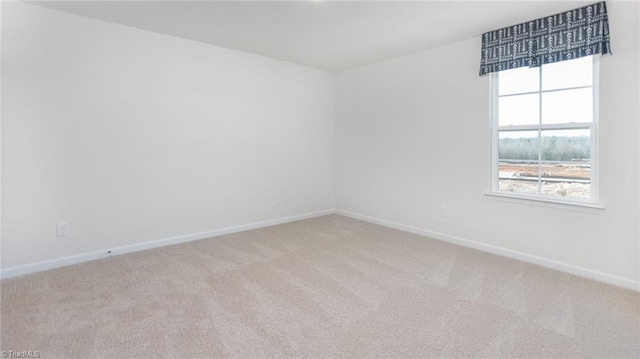 empty room featuring baseboards and light colored carpet