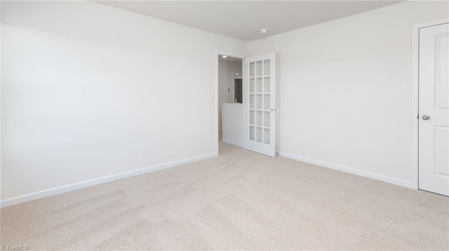 unfurnished room featuring baseboards and light carpet