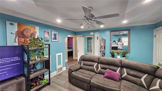 living room with ceiling fan, ornamental molding, hardwood / wood-style floors, and a fireplace