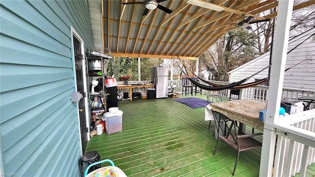 wooden deck with exterior bar and ceiling fan