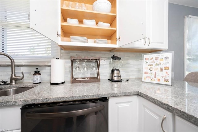 kitchen featuring dishwasher, a sink, white cabinetry, backsplash, and light stone countertops