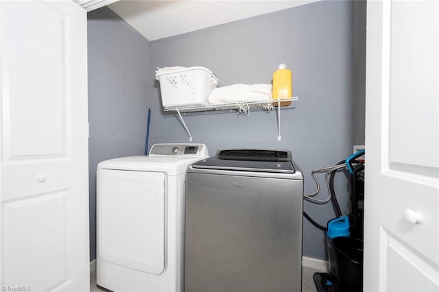washroom with washing machine and dryer and baseboards