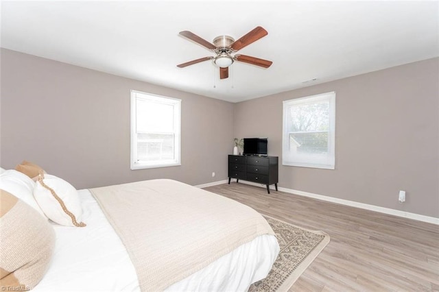 bedroom with light wood-style flooring, baseboards, and a ceiling fan
