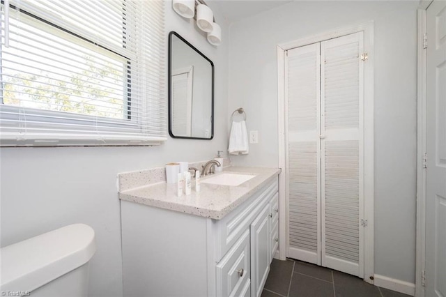 half bath with tile patterned flooring, vanity, and toilet