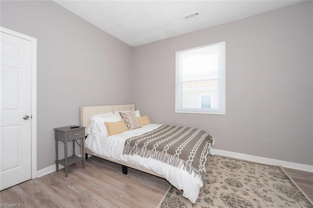 bedroom with wood finished floors, baseboards, and vaulted ceiling