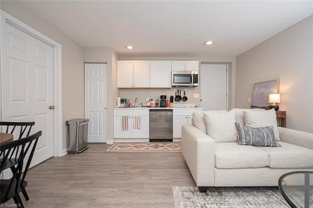 kitchen with stainless steel appliances, light wood-style flooring, open floor plan, white cabinets, and recessed lighting