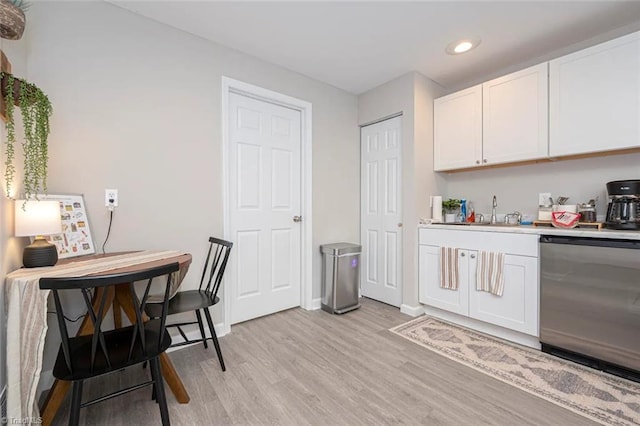 kitchen with dishwashing machine, a sink, light wood finished floors, recessed lighting, and white cabinets