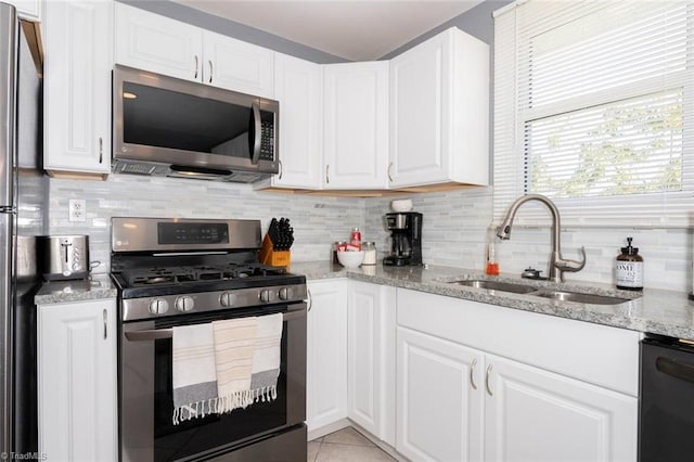 kitchen with stainless steel appliances, a sink, backsplash, and white cabinets