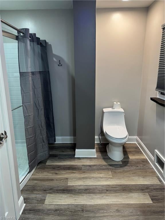 bathroom with curtained shower, wood-type flooring, and toilet