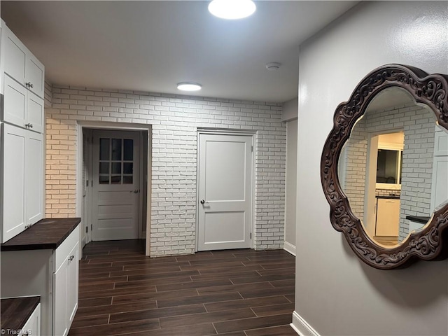 hallway with dark hardwood / wood-style flooring and brick wall