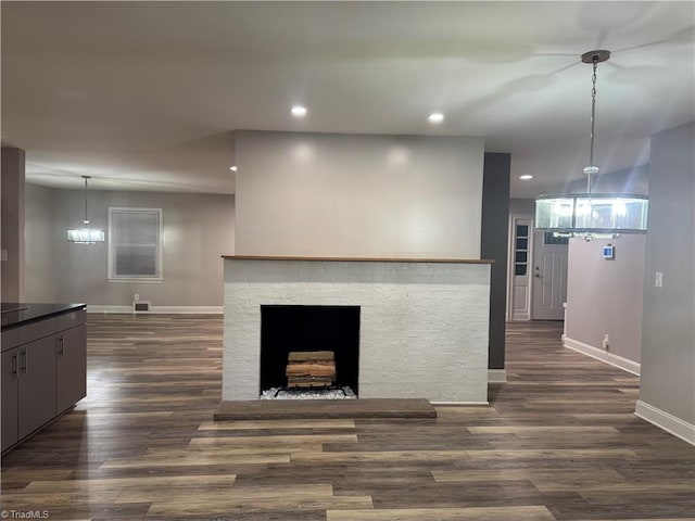 living room featuring a stone fireplace, dark hardwood / wood-style floors, and a chandelier