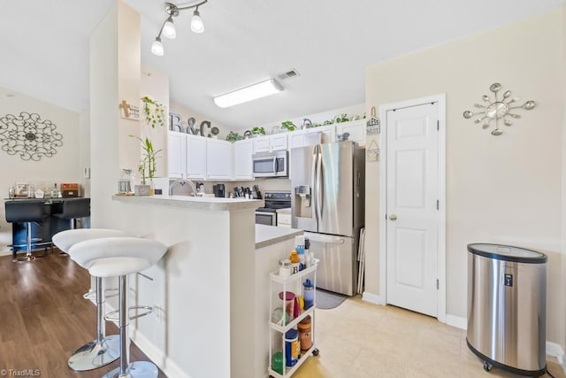 6112 Hedgecock Cir Unit 3B, High Point, NC 27265 - kitchen featuring stainless steel appliances, a breakfast bar, a peninsula, light countertops, and white cabinetry