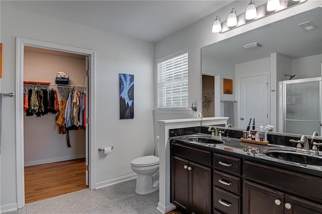 4548 River Gate Dr, Clemmons, NC 27012 - bathroom featuring a shower stall, baseboards, double vanity, toilet, and a spacious closet