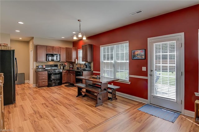 4548 River Gate Dr, Clemmons, NC 27012 - kitchen featuring black appliances, light wood-style floors, dark countertops, a chandelier, and baseboards