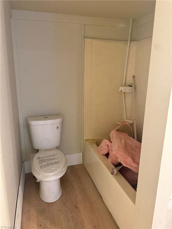 bathroom with wood-type flooring, toilet, and a bath