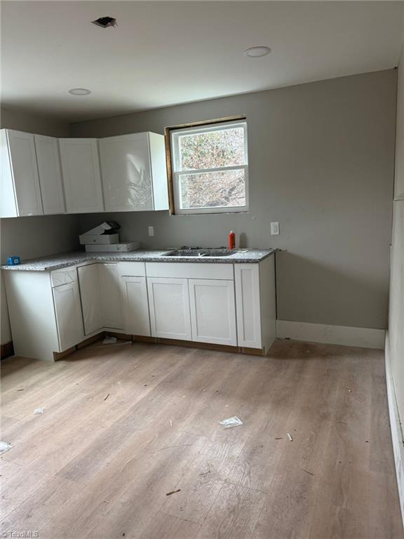 kitchen featuring sink, white cabinets, and light hardwood / wood-style flooring