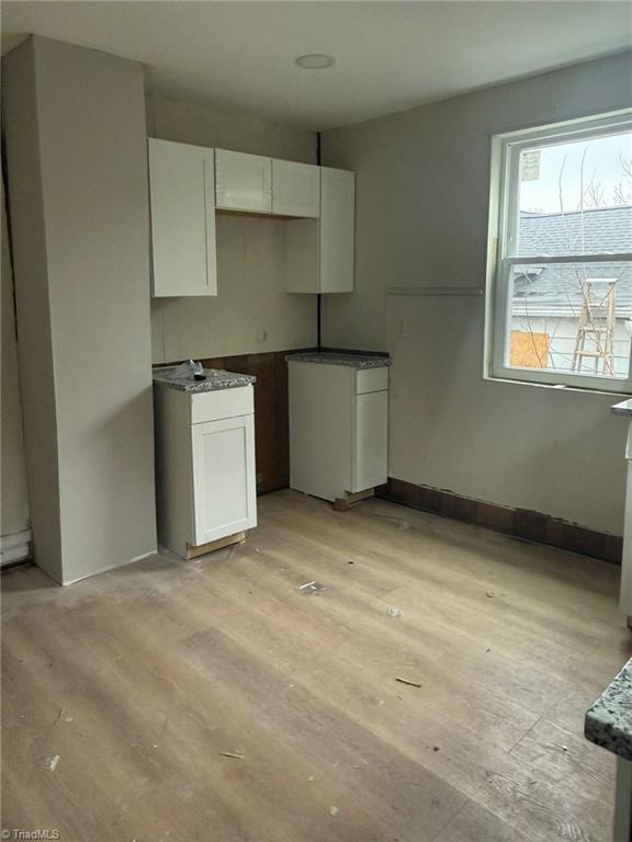 kitchen with light wood-type flooring and white cabinetry