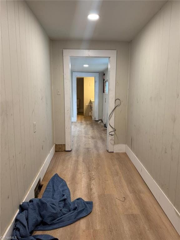 hallway with wooden walls and light hardwood / wood-style flooring